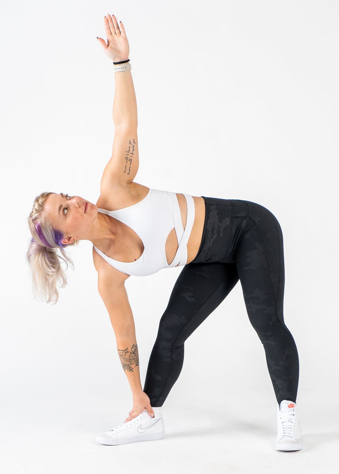 Full Body Front View Woman Bent to the Side with One Arm Touching the Ground and the Other in the Air Wearing Empowered Leggings x FIT OPS | Black Camo