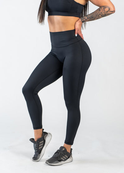 Chest Down Side View with Hands on Lower Back Wearing Empowered Leggings | Black