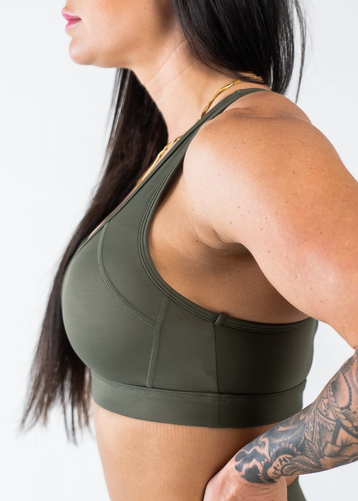 Waist Up Side View with Hand on Lower Back Wearing Empowered Laced Back Sports Bra | OD Green