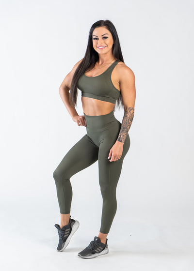 Full Body 3/4 Front View One Leg Up Wearing Empowered Leggings With Pockets | OD Green