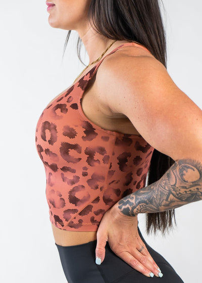 Waist Up Side View Hands on Lower Back Wearing Empowered Crop Bra | Orange Leopard