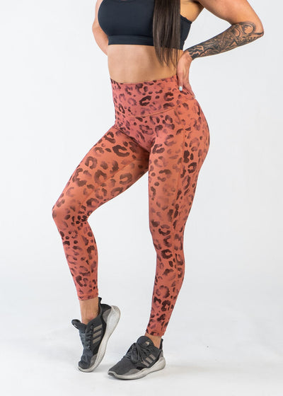 Chest Down 3/4 Front View One Leg Up Wearing Empowered Leggings With Pockets | Orange Leopard