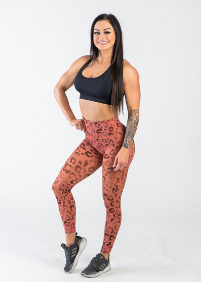 Full Body 3/4 Front View One Leg Up Wearing Empowered Leggings With Pockets | Orange Leopard