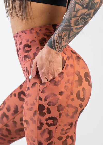 Chest to Thigh Side View with Hand in Pocket Wearing Empowered Leggings With Pockets | Orange Leopard