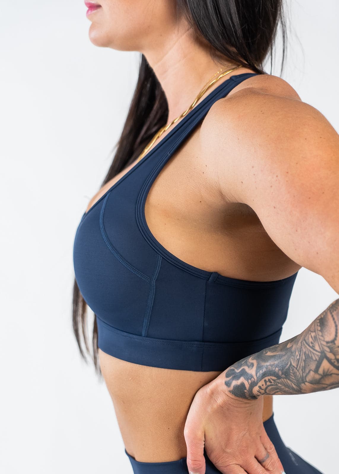 Waist Up Side View with Hand on Lower Back Wearing Empowered Laced Back Sports Bra | Blue