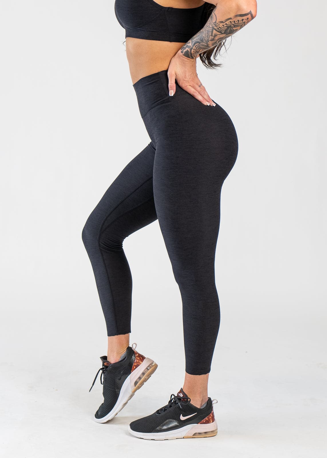 Chest Down Side View With One Hand on Lower Back Wearing Dream Leggings | Black
