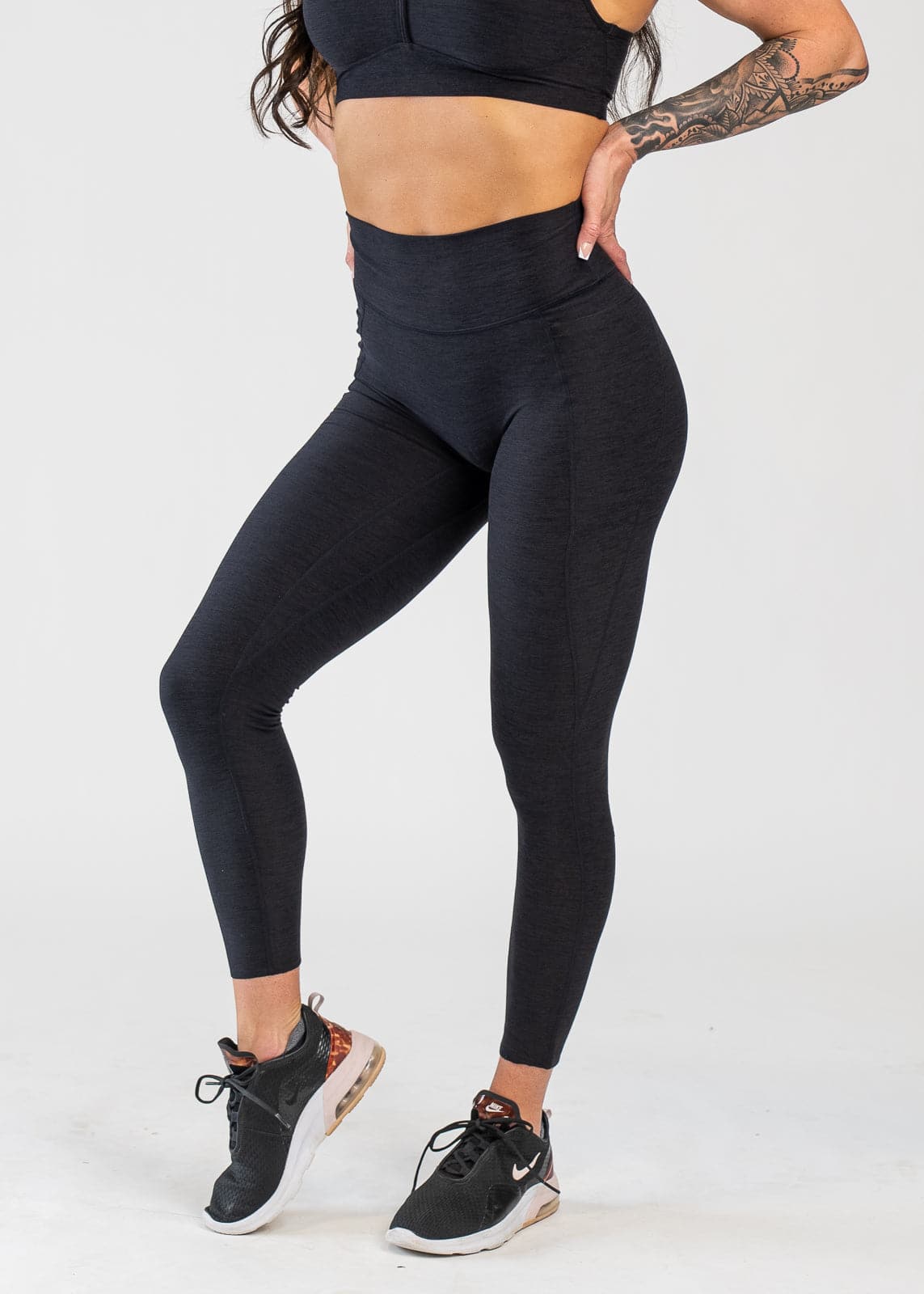 Chest Down 3/4 Front View With One Hand on Lower Back Wearing Dream Leggings With Pockets | Black