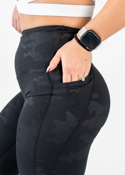Chest to Thigh Side View with Hand in Pocket Wearing Empowered Leggings x FIT OPS | Black Camo