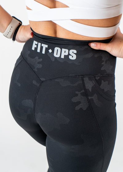 Chest to Thigh 3/4 Back View with Hands on Sides Wearing Empowered Leggings x FIT OPS | Black Camo