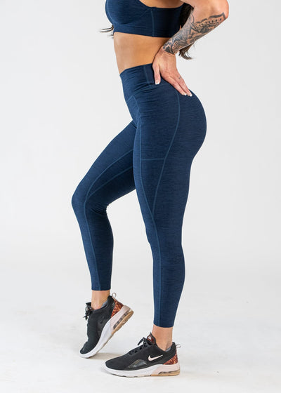 Chest Down Side View With One Hand on Lower Back Wearing Dream Leggings With Pockets | Deep Blue