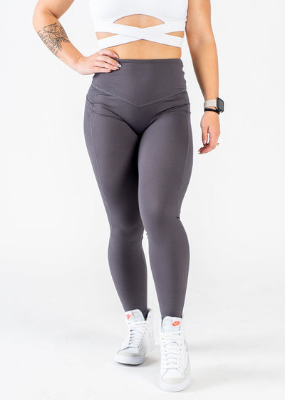 Chest Down Front View One Hand on Hip Wearing Empowered Leggings x FIT OPS | Grey